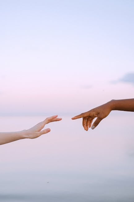 Oferta Two diverse hands reaching towards each other over a serene pastel sky and water background.